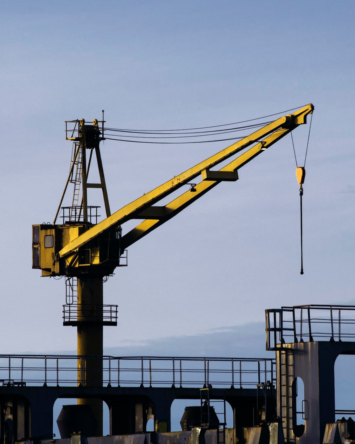Marine derrick crane lit by evening light over the waterfront