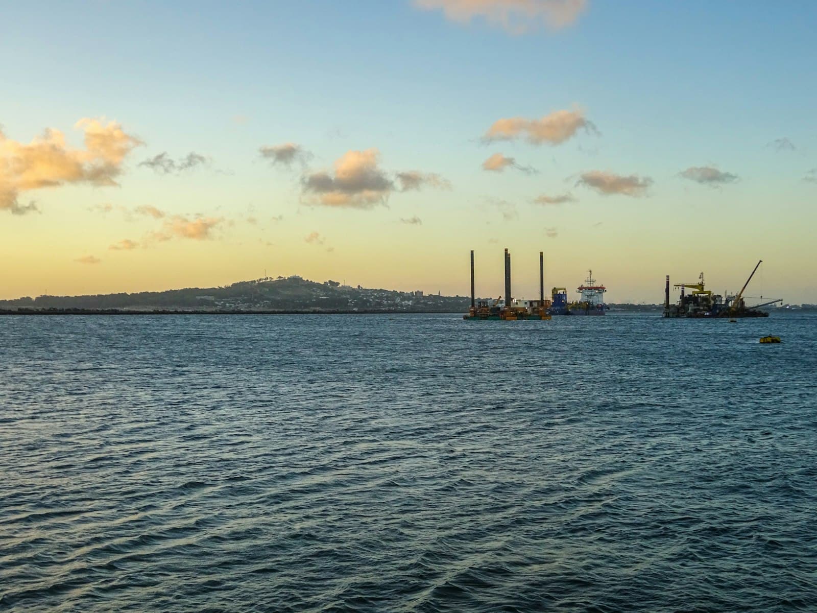 Construction barges moored off a wooded island
