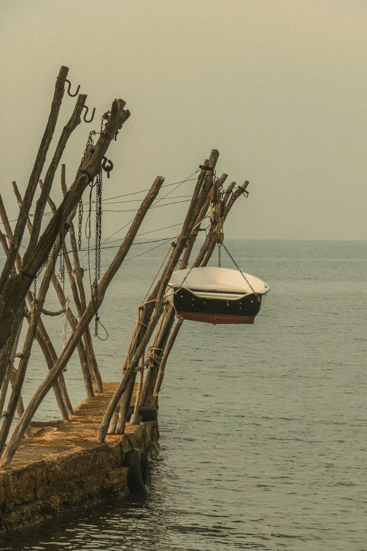 Boat in slings over the water on a timber davit