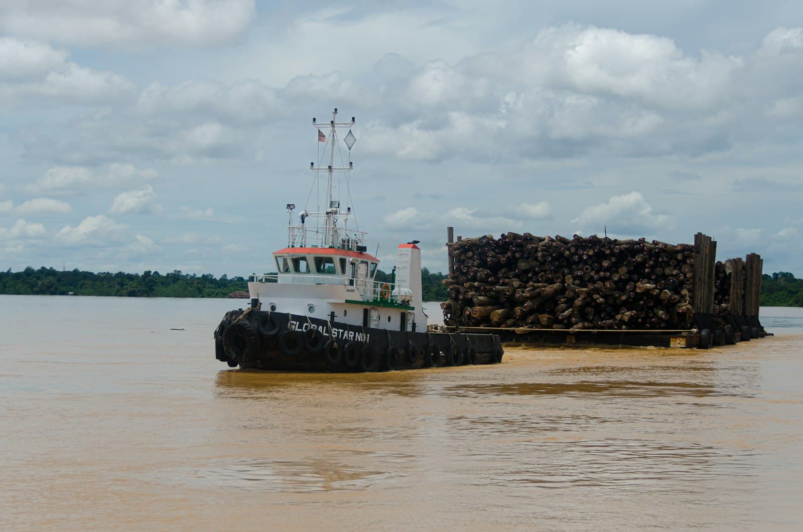 Tug pushing a loaded barge down a working river